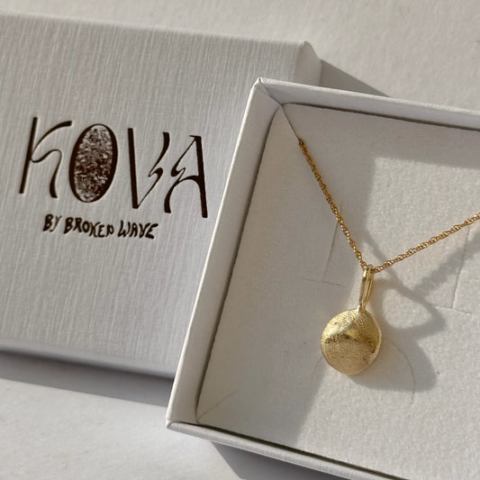 Gold necklace with a pendant on a branded box